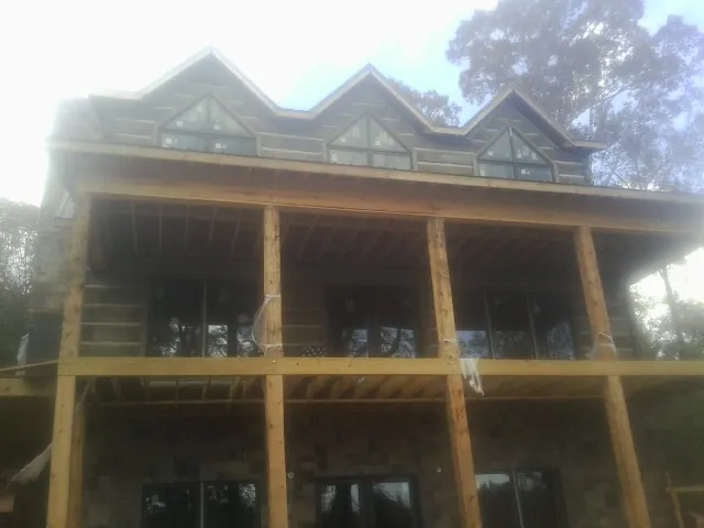 Dormers and porch framing on a large log home under construction — Roof Coating work by our crew in Denton